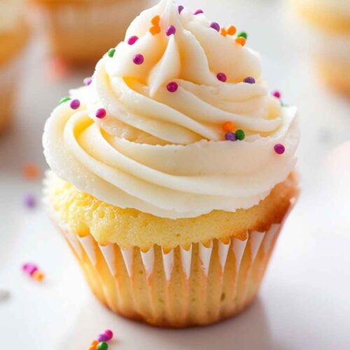 Mini Cupcakes – Bite-Sized Bakes for Every Occasion 5 Vanilla mini cupcake with buttercream frosting and colorful sprinkles on a white surface