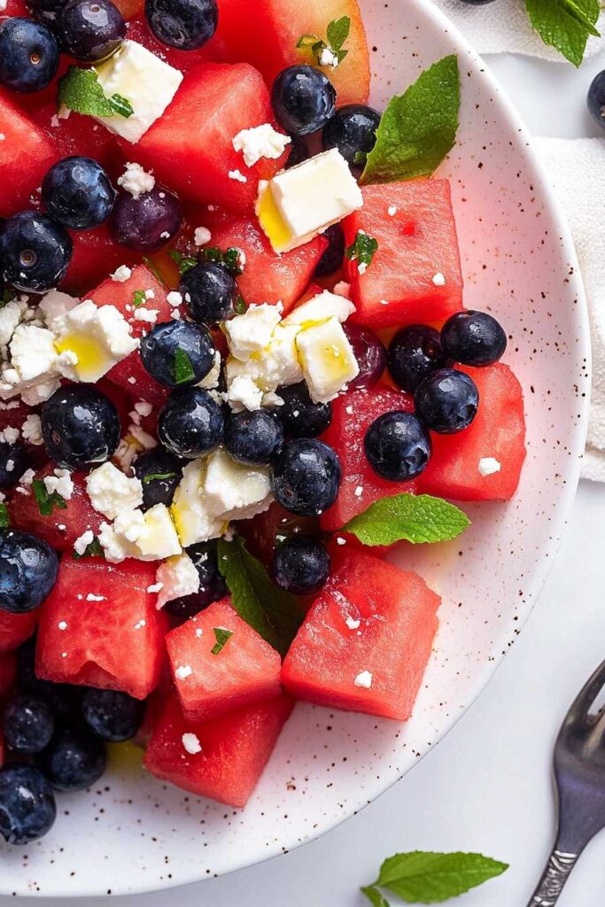 Watermelon Blueberry and Feta Cheese Salad – A Refreshing Summer Delight 5 Freshly prepared Watermelon Blueberry and Feta Cheese Salad with olive oil drizzle and mint leaves.